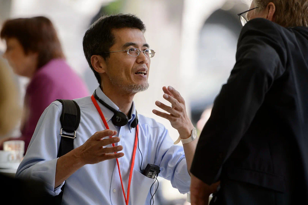 A Man In Glasses Engaged In Conversation With Another Professional.