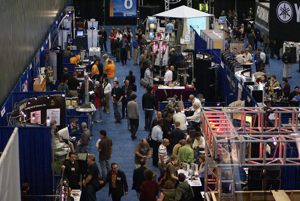 Crowds Of Attendees Interacting With A Variety Of Trade Show Booths.