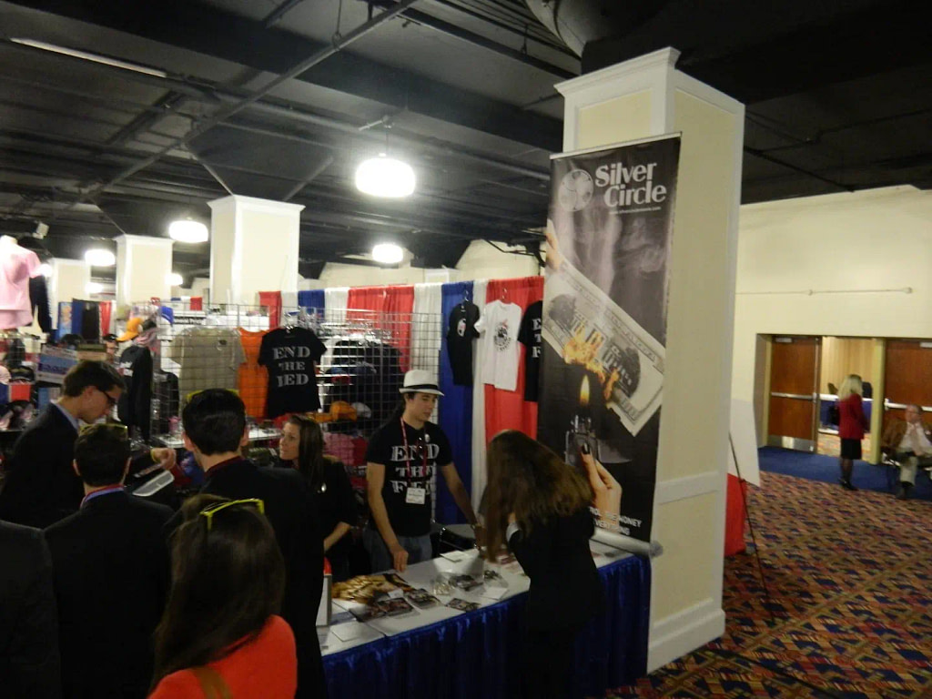 Attendees Gather Around A Clothing Retailer'S Trade Show Booth.