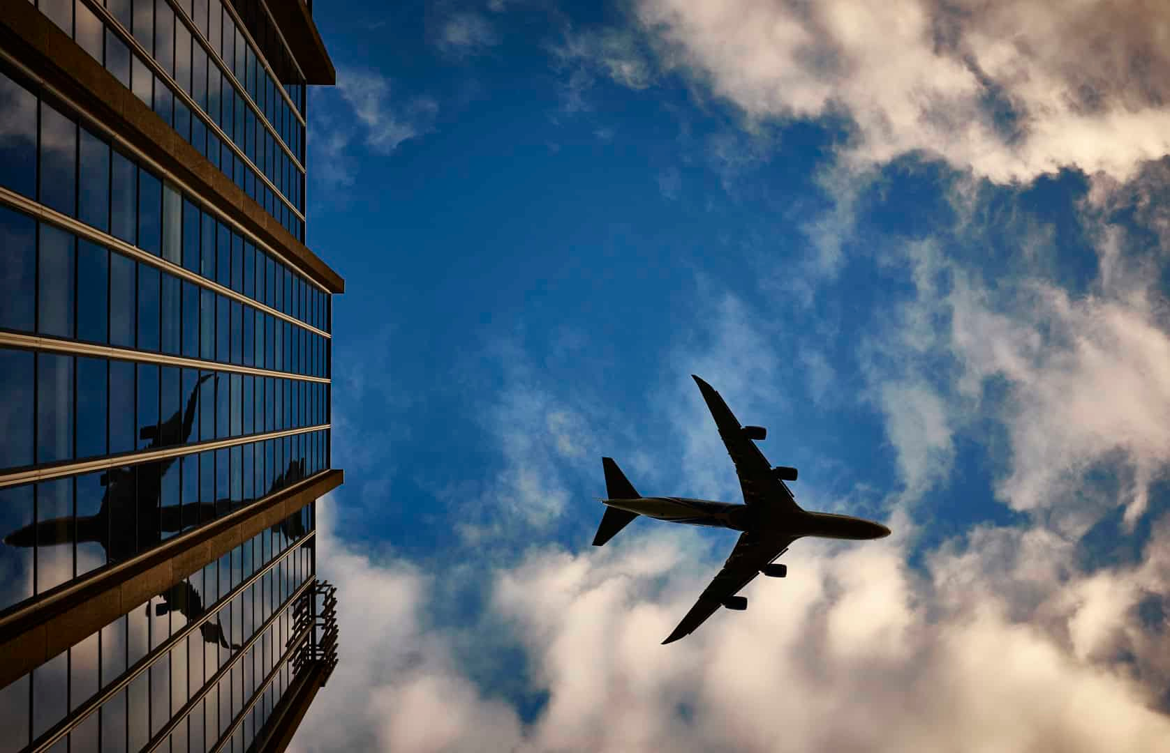 A Passenger Airliner Flying Over A Building At Low Altitude. 