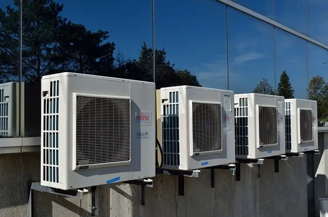 Four White Air Conditioning Units On The Side Of A Building.