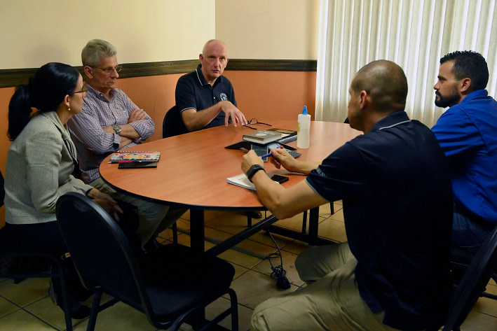 A Team Of Five People Sit Down And Discuss Matters At A Table. 
