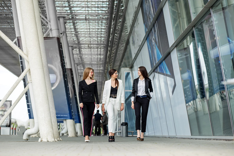 A group of women in professional attire walking down a walkway.