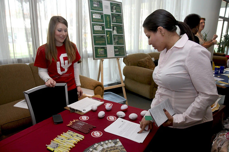 A professional trade show attendee examines a form on an exhibitors desk.